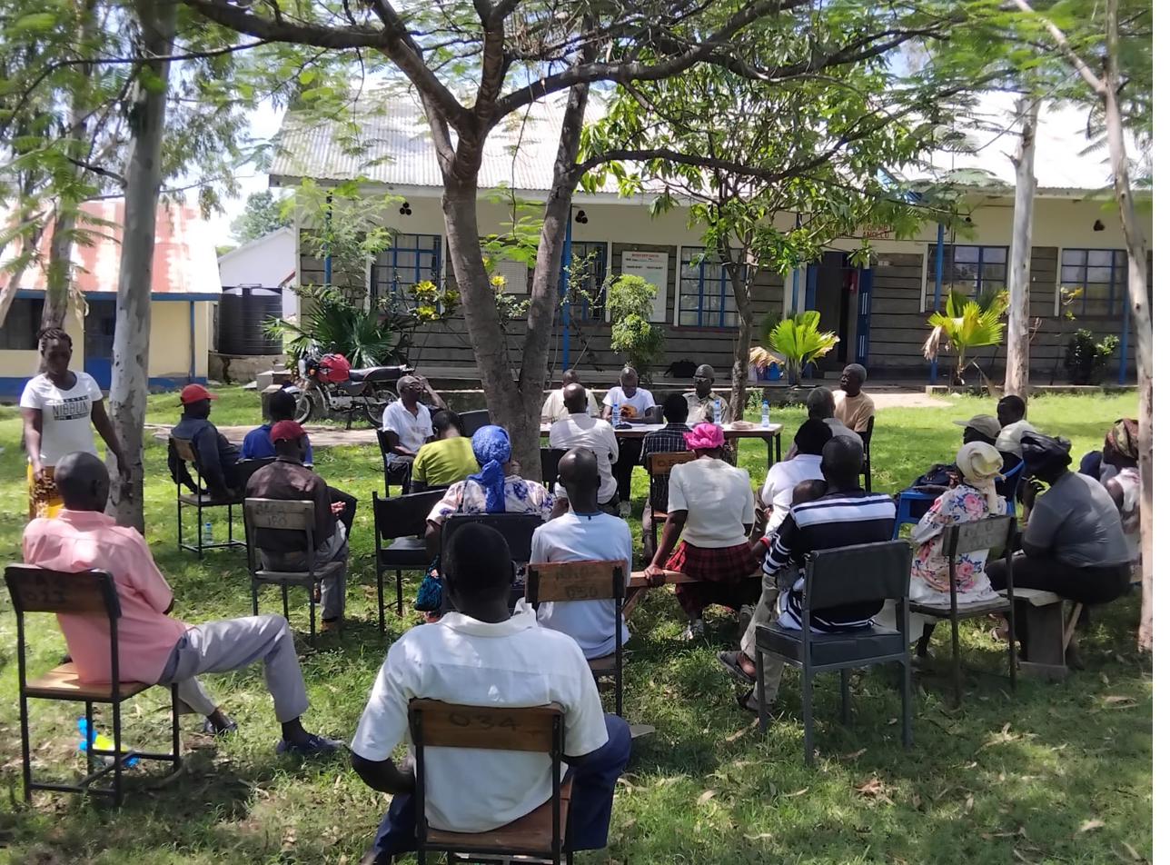 Community meeting under the trees at the school